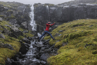 Seitenansicht eines Wanderers, der gegen einen Wasserfall springt - CAVF57928