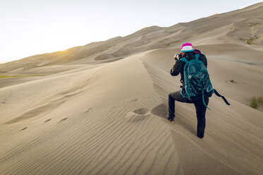 Rear view of hiker with backpack photographing at Great Sand Dunes National Park - CAVF57945