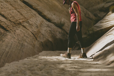 Seitenansicht einer Frau, die auf Sand inmitten von Felsformationen läuft - CAVF57949