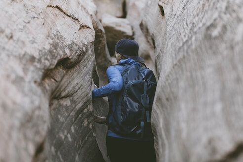 Rear view of female hiker with backpack canyoneering amidst narrow canyons - CAVF57950