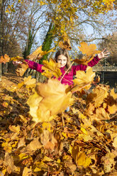 Girl throwing autumn leaves in the air - SARF03997