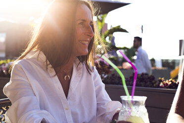 Glückliche Frau in einer Bar bei Sonnenuntergang mit Cocktailglas - ERRF00236