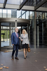 Senior businessman and businesswoman walking and talking in a foyer - MAUF01791