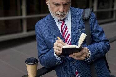 Älterer Geschäftsmann schreibt im Freien in sein Tagebuch - MAUF01801