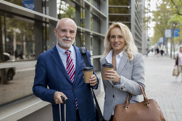 Porträt eines lächelnden älteren Geschäftsmannes und einer Geschäftsfrau mit Gepäck, die in der Stadt unterwegs sind - MAUF01804