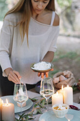 Frau bereitet ein romantisches Essen bei Kerzenschein im Freien vor - ALBF00708