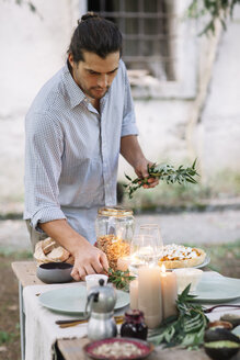 Mann bei der Zubereitung einer romantischen Mahlzeit bei Kerzenlicht im Freien - ALBF00712