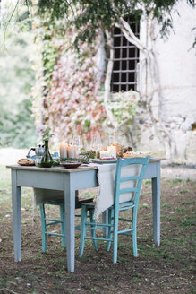 Laid garden table with candles next to a cottage - ALBF00720
