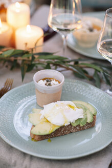 Bread with avocado and dessert on garden table with candles - ALBF00721