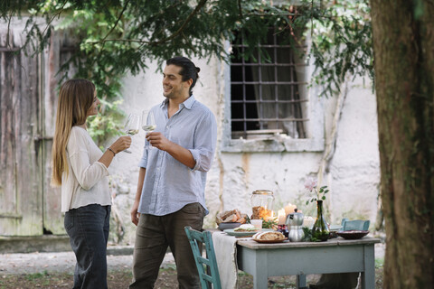 Couple with wine glasses having a romantic candelight meal next to a cottage stock photo