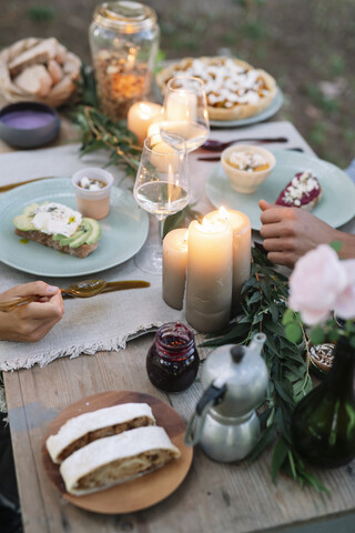 Nahaufnahme eines Paares bei einer romantischen Mahlzeit bei Kerzenschein im Freien, lizenzfreies Stockfoto