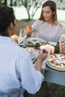 Couple having a romantic candlelight meal in garden - ALBF00728