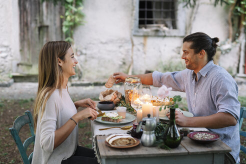 Glückliches Paar bei einer romantischen Mahlzeit im Kerzenschein neben einer Hütte - ALBF00729