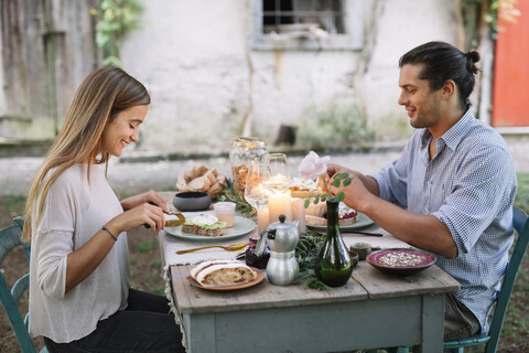 Paar bei einem romantischen Essen bei Kerzenlicht neben einer Hütte, lizenzfreies Stockfoto