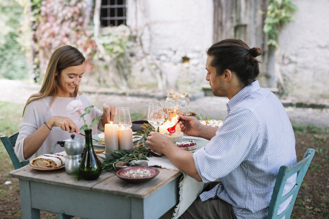 Paar bei einem romantischen Essen bei Kerzenlicht neben einer Hütte, lizenzfreies Stockfoto