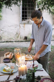 Man arranging a romantic candlelight meal outdoors - ALBF00734