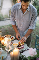 Mann arrangiert ein romantisches Essen bei Kerzenschein im Freien - ALBF00735