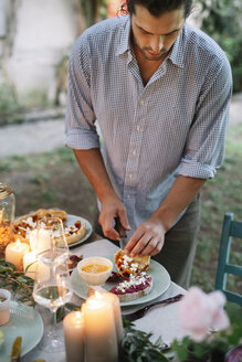 Man arranging a romantic candlelight meal outdoors - ALBF00735