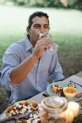 Mann trinkt ein Glas Wein am Gartentisch - ALBF00737