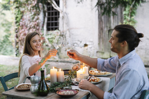 Paar bei einem romantischen Essen bei Kerzenschein neben einer Hütte, das mit Weingläsern anstößt - ALBF00738