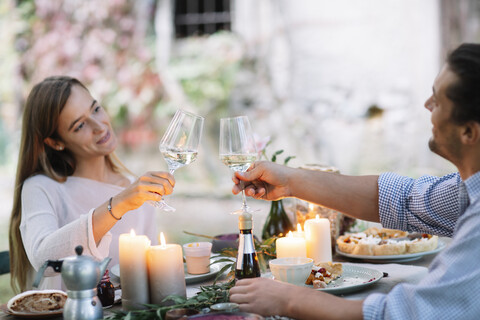 Couple having a romantic candlelight meal clinking wine glasses stock photo