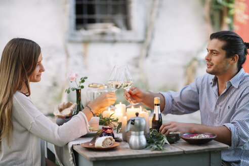 Paar bei einem romantischen Essen bei Kerzenlicht und stößt mit Weingläsern an - ALBF00742