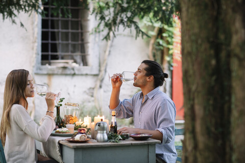 Pärchen bei einem romantischen Essen bei Kerzenlicht, das aus Weingläsern trinkt, lizenzfreies Stockfoto