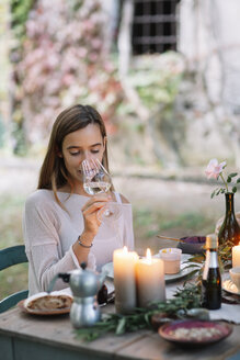 Woman tasting glass of wine at garden table - ALBF00745