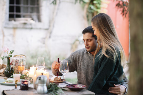 Romantisches Paar beim Essen im Kerzenschein am Gartentisch, lizenzfreies Stockfoto