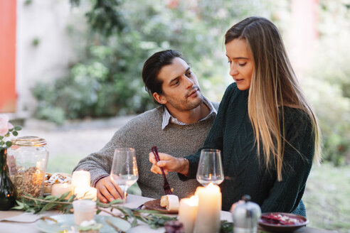 Romantic couple having a candlelight meal at garden table - ALBF00748