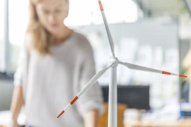 Wind turbine model and woman in background in office - TCF06013