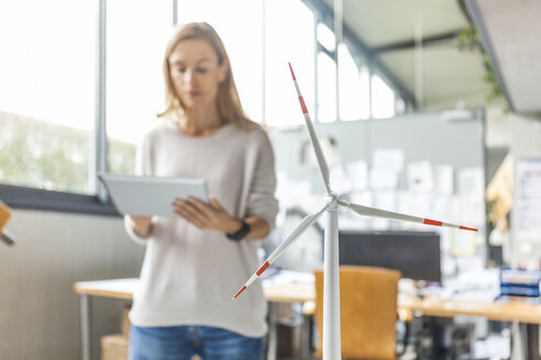 Woman in office with wind turbine model using tablet - TCF06015
