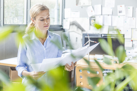 Frau im Büro arbeitet an einem Plan mit einem Windradmodell auf dem Tisch, lizenzfreies Stockfoto