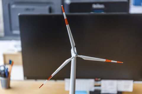 Close-up of wind turbine model and desktop computer in office stock photo