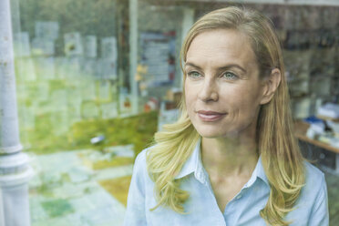 Portrait of woman in office behind windowpane - TCF06038