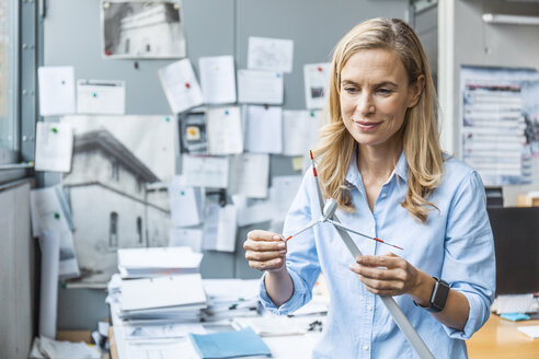 Selbstbewusste Frau im Büro, die ein Windradmodell hält - TCF06041