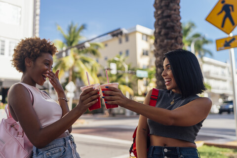 USA, Florida, Miami Beach, zwei glückliche Freundinnen bei einem Softdrink in der Stadt, lizenzfreies Stockfoto