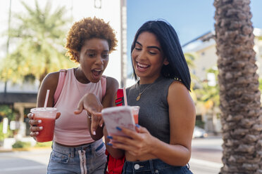 USA, Florida, Miami Beach, zwei glückliche Freundinnen mit Handy und Softdrink in der Stadt - BOYF01172