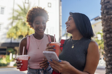 USA, Florida, Miami Beach, zwei glückliche Freundinnen mit Handy und Softdrink in der Stadt - BOYF01173