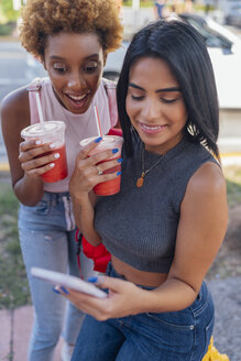 USA, Florida, Miami Beach, zwei glückliche Freundinnen mit Handy und Softdrink in der Stadt - BOYF01176