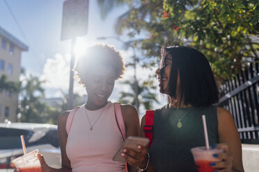 USA, Florida, Miami Beach, zwei glückliche Freundinnen mit Handy und Softdrink in der Stadt - BOYF01184