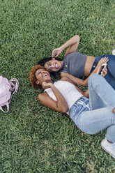 Zwei glückliche Freundinnen entspannen sich in einem Park und hören Musik - BOYF01192