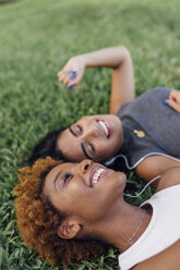Porträt von zwei glücklichen Freundinnen, die sich in einem Park entspannen und Musik hören - BOYF01193
