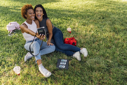 Zwei glückliche Freundinnen machen ein Sofortfoto in einem Park - BOYF01201