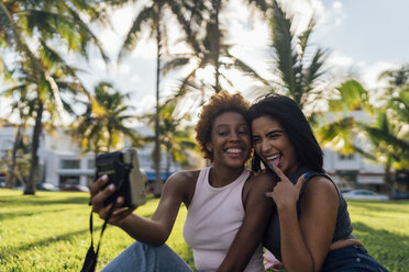 Two happy female friends taking an instant photo in a park - BOYF01202