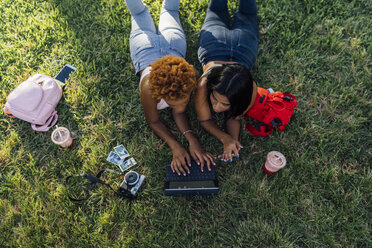 Zwei Freundinnen entspannen sich in einem Park und benutzen ein Tablet - BOYF01207