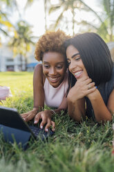 Portrait of two happy female friends relaxing in a park using a tablet - BOYF01209