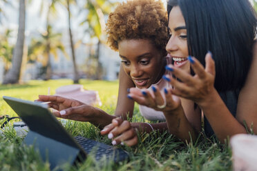 Portrait of two happy female friends relaxing in a park using a tablet - BOYF01210