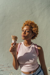 Portrait of young woman with ice cream cone at a wall - BOYF01228