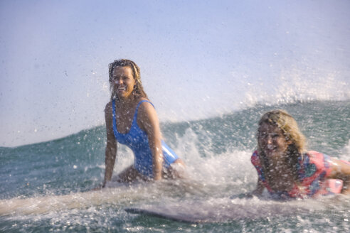 Indonesien, Bali, Batubolong Strand, junge Surferinnen auf dem Brett, Wasser spritzen - KNTF02459